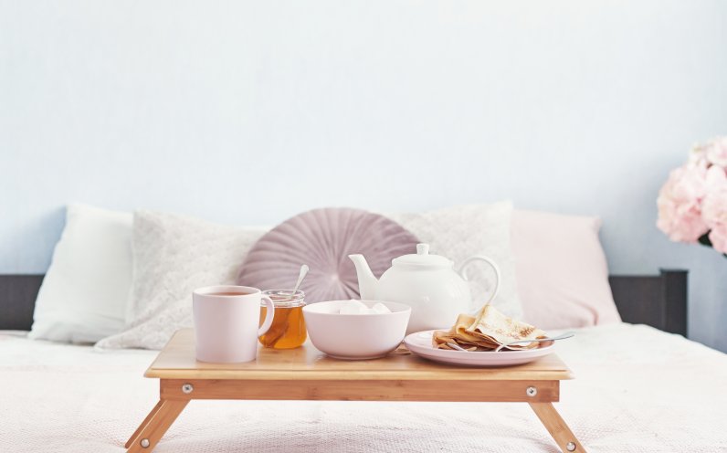 Image shows breakfast on a serving tray on a bed